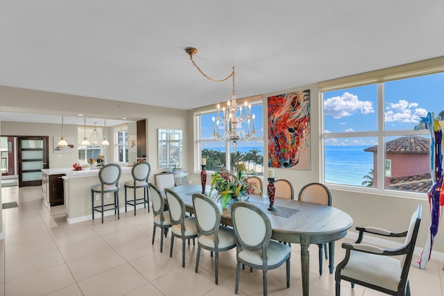 tiled dining room with a notable chandelier, a water view, and a wealth of natural light