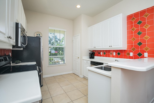 kitchen with light tile patterned floors, backsplash, kitchen peninsula, white cabinets, and appliances with stainless steel finishes