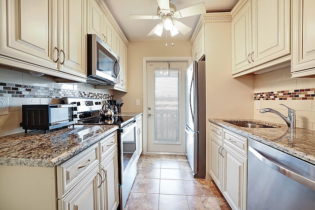 kitchen with light stone countertops, appliances with stainless steel finishes, decorative backsplash, and sink