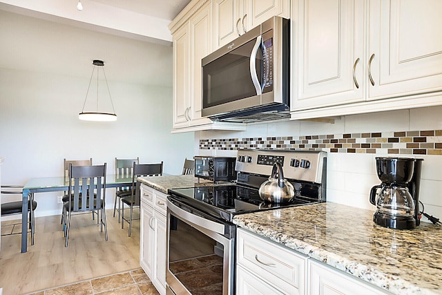 kitchen featuring backsplash, pendant lighting, stainless steel appliances, and light wood-type flooring