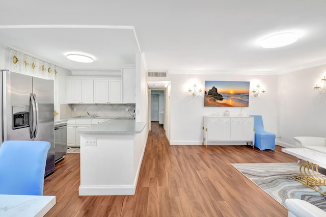 kitchen featuring backsplash, white cabinetry, light wood-type flooring, and appliances with stainless steel finishes