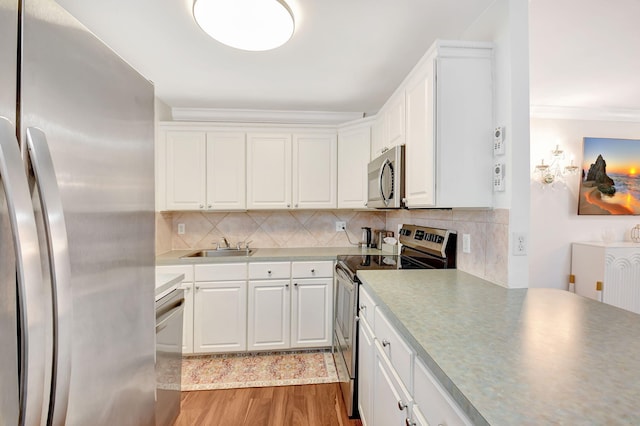 kitchen with backsplash, dark wood-type flooring, white cabinets, ornamental molding, and stainless steel appliances