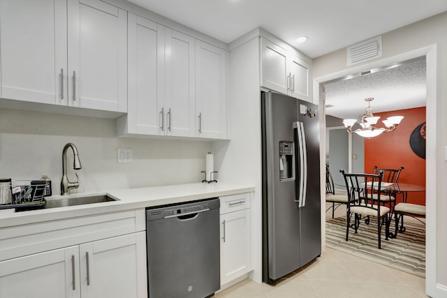 kitchen featuring stainless steel appliances, sink, light tile patterned floors, an inviting chandelier, and white cabinetry