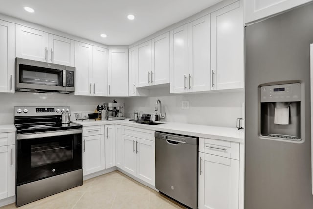 kitchen with light tile patterned floors, white cabinetry, sink, and appliances with stainless steel finishes