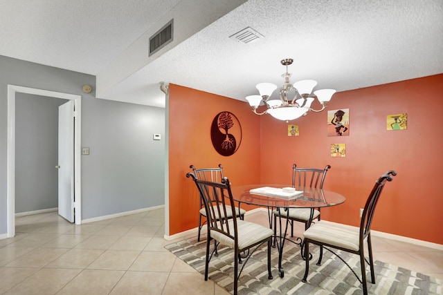 tiled dining area featuring a chandelier and a textured ceiling