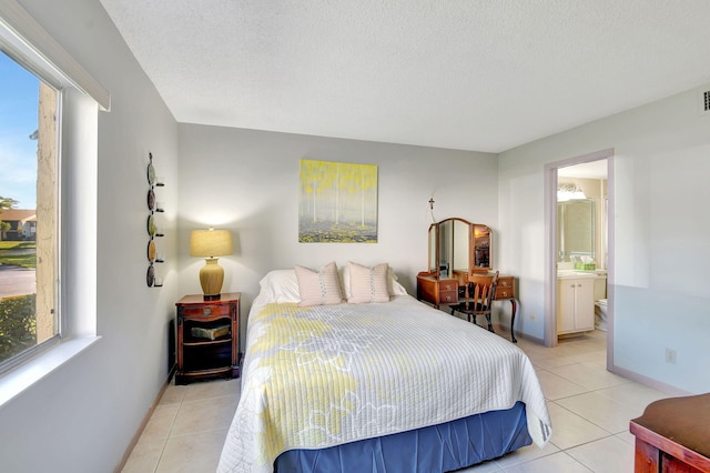 bedroom featuring light tile patterned flooring, ensuite bathroom, and a textured ceiling