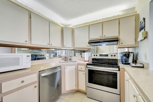 kitchen with sink, stainless steel appliances, a textured ceiling, light tile patterned flooring, and cream cabinetry