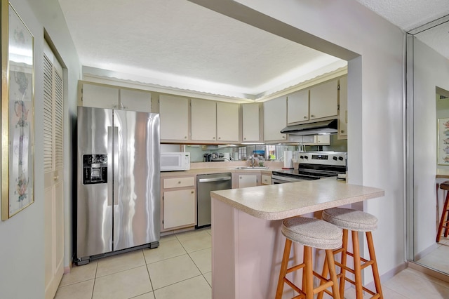 kitchen with sink, light tile patterned flooring, a kitchen breakfast bar, and appliances with stainless steel finishes