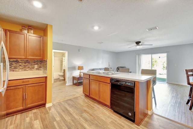 kitchen with dishwasher, light hardwood / wood-style floors, sink, and a kitchen island with sink