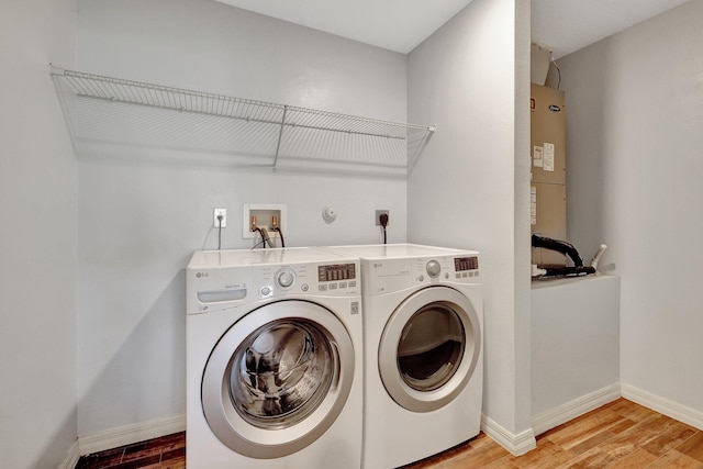 washroom with hardwood / wood-style flooring, washing machine and dryer, and gas water heater