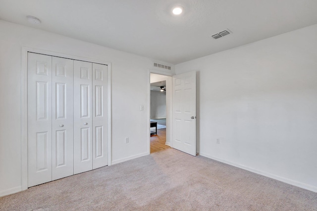 unfurnished bedroom featuring light colored carpet and a closet