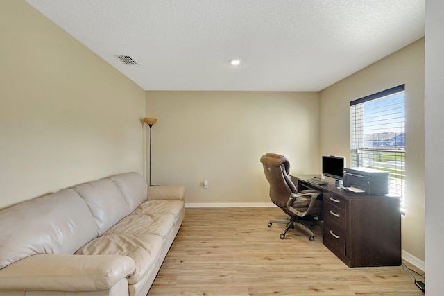 office space featuring light wood-type flooring and a textured ceiling