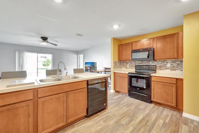 kitchen with black appliances, sink, light hardwood / wood-style flooring, ceiling fan, and tasteful backsplash