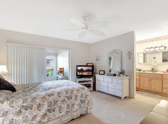 bedroom featuring ceiling fan, ensuite bathroom, and light colored carpet