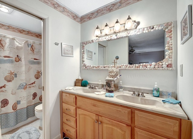 full bathroom with double vanity, a sink, toilet, and ceiling fan