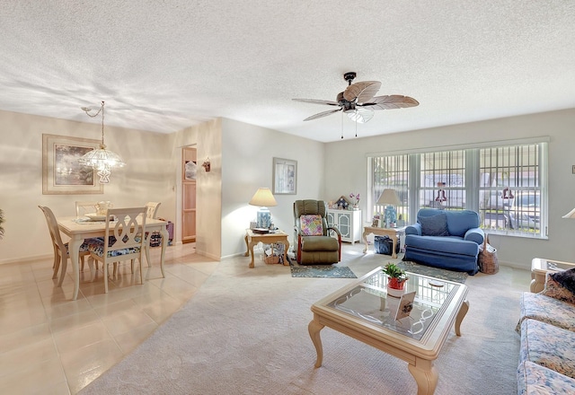 tiled living area featuring carpet flooring, a textured ceiling, baseboards, and ceiling fan with notable chandelier