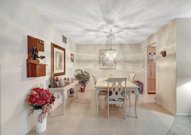 dining space featuring light tile patterned floors, visible vents, baseboards, a textured ceiling, and a chandelier