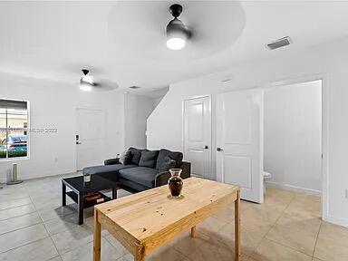 tiled living room with ceiling fan