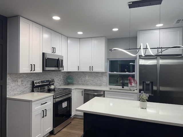 kitchen with white cabinets, appliances with stainless steel finishes, pendant lighting, and sink