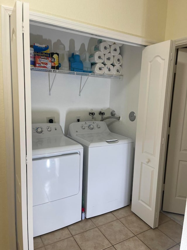 laundry room with washer and clothes dryer and light tile patterned floors