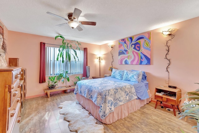 bedroom with a textured ceiling, light hardwood / wood-style flooring, and ceiling fan