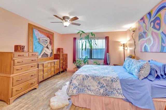 bedroom featuring ceiling fan, light hardwood / wood-style floors, and a textured ceiling