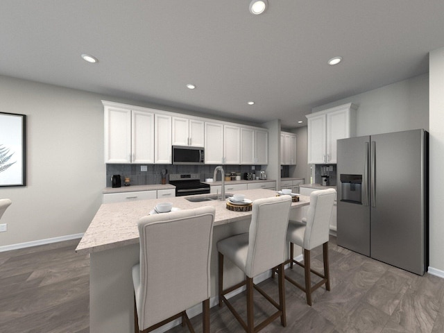 kitchen featuring sink, a kitchen island with sink, a breakfast bar, white cabinets, and appliances with stainless steel finishes