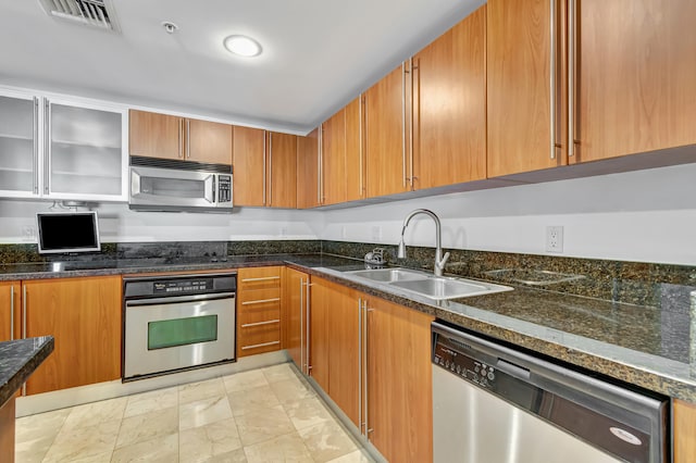 kitchen featuring dark stone countertops, sink, and stainless steel appliances