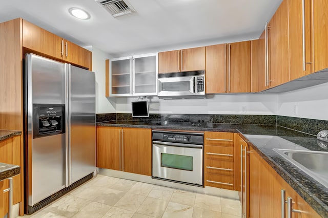 kitchen featuring dark stone countertops, sink, and stainless steel appliances