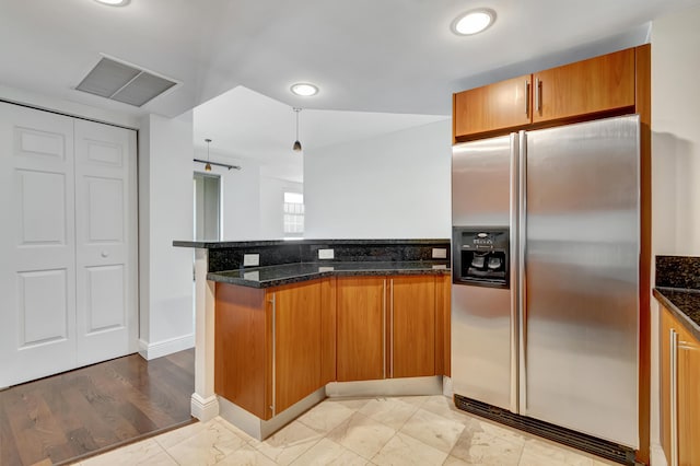 kitchen featuring light hardwood / wood-style floors, dark stone countertops, stainless steel fridge with ice dispenser, and kitchen peninsula