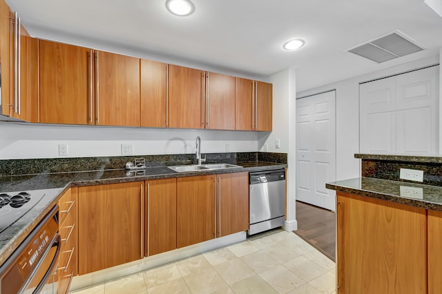 kitchen featuring dark stone countertops, sink, stainless steel dishwasher, and light hardwood / wood-style flooring