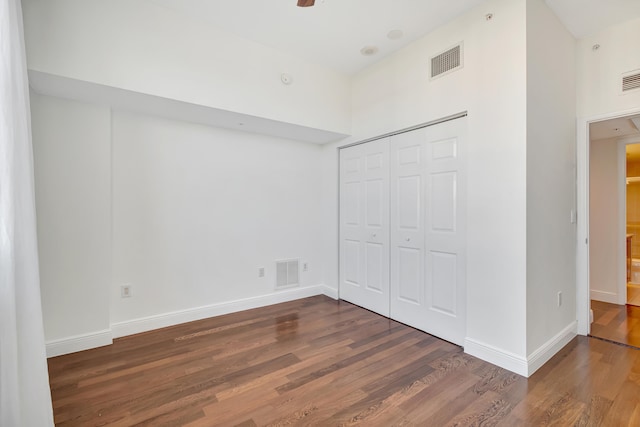 unfurnished bedroom featuring dark hardwood / wood-style flooring, a high ceiling, and a closet