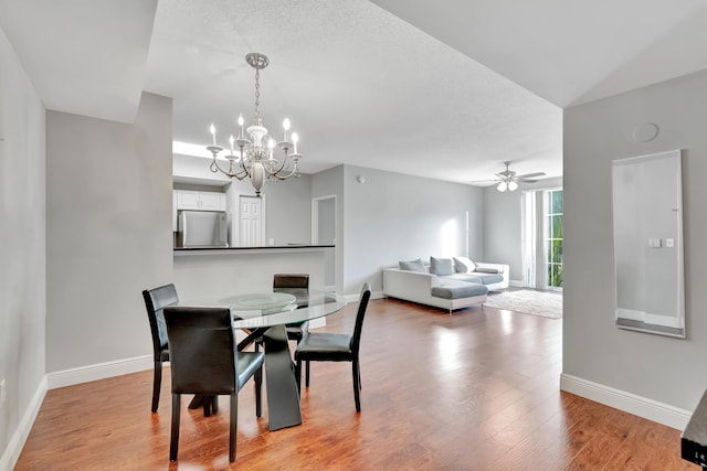 dining space featuring a textured ceiling, ceiling fan with notable chandelier, and light hardwood / wood-style flooring