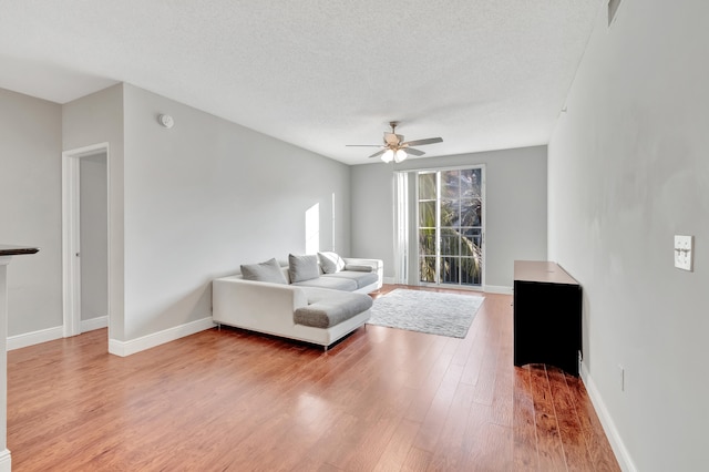 living room with ceiling fan, wood-type flooring, and a textured ceiling