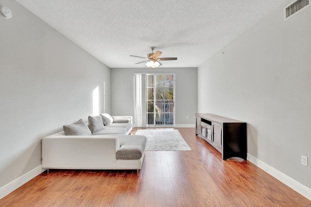 living room with ceiling fan, light hardwood / wood-style floors, and a textured ceiling