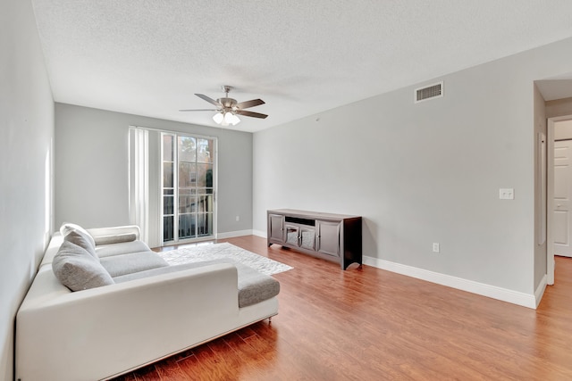 living room with ceiling fan, wood-type flooring, and a textured ceiling