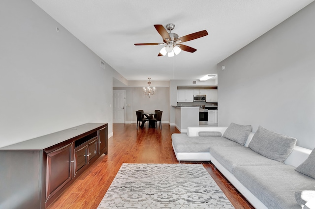 living room featuring hardwood / wood-style floors and ceiling fan with notable chandelier