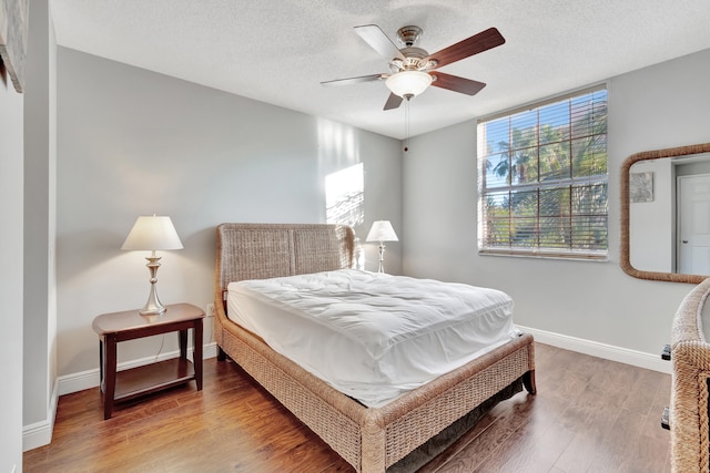 bedroom featuring ceiling fan, hardwood / wood-style floors, and a textured ceiling