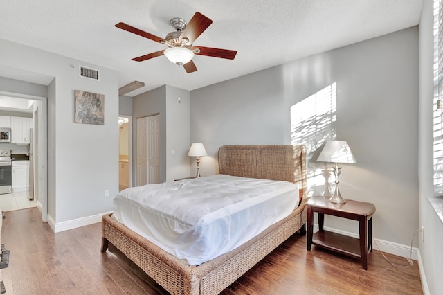 bedroom featuring hardwood / wood-style floors, ceiling fan, a textured ceiling, connected bathroom, and a closet