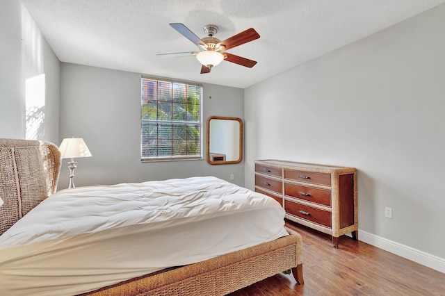 bedroom with ceiling fan, a textured ceiling, and hardwood / wood-style flooring