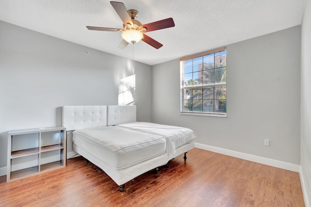 bedroom featuring hardwood / wood-style flooring, ceiling fan, and a textured ceiling