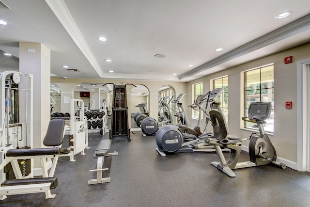 workout area with a raised ceiling and ornamental molding