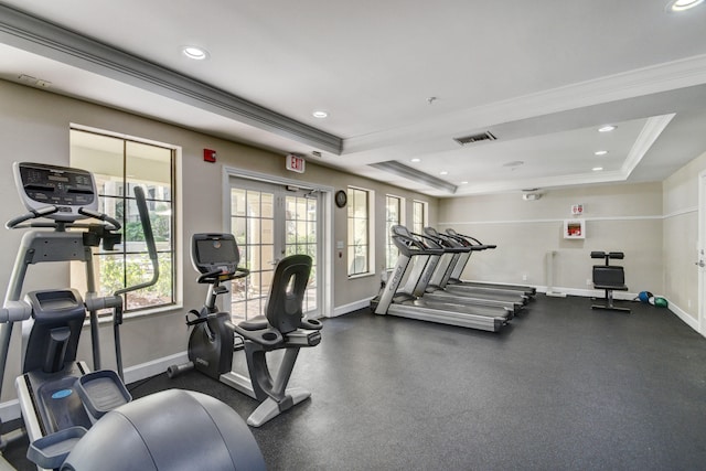 workout area featuring a raised ceiling and ornamental molding