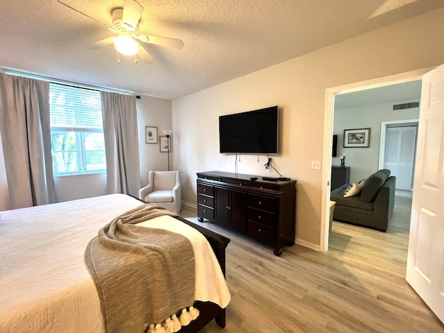 bedroom with ceiling fan, light wood-type flooring, and a textured ceiling