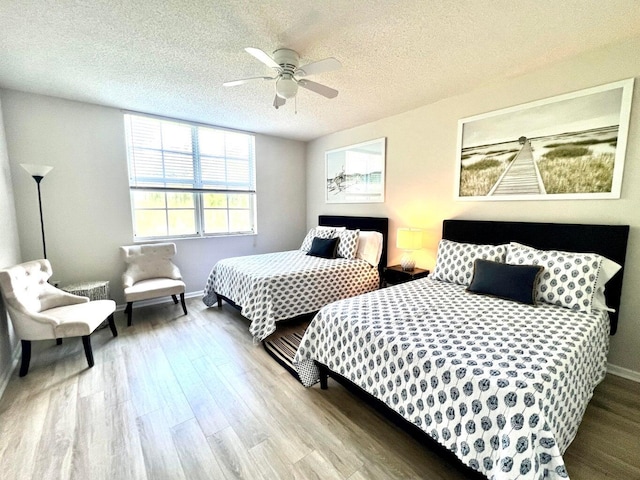 bedroom featuring ceiling fan, light wood-type flooring, and a textured ceiling