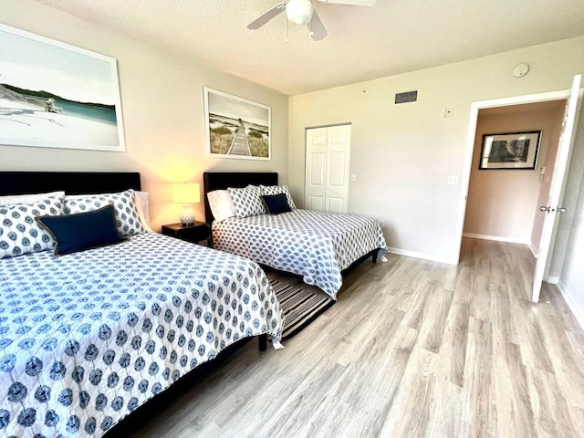 bedroom featuring ceiling fan, a closet, light hardwood / wood-style floors, and a textured ceiling