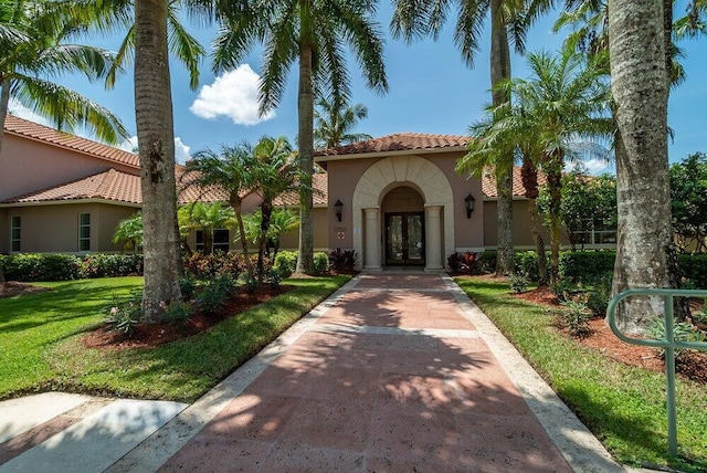 mediterranean / spanish-style home featuring french doors and a front lawn