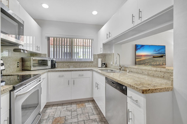 kitchen with decorative backsplash, white cabinetry, sink, and appliances with stainless steel finishes