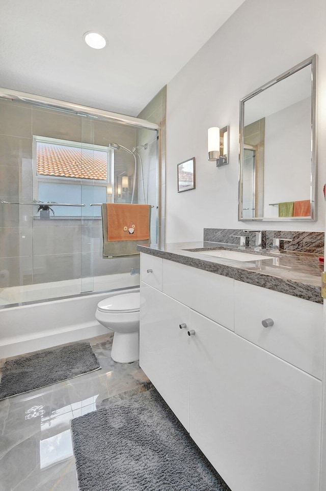 full bathroom with vanity, toilet, and shower / bath combination with glass door