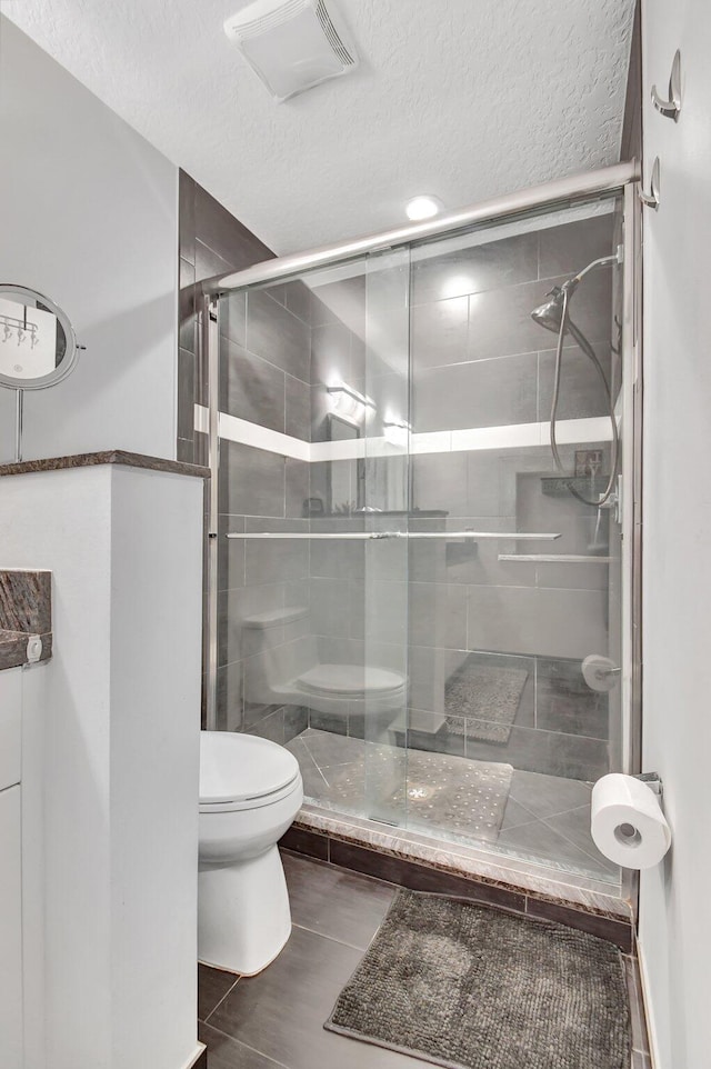 bathroom with a textured ceiling, toilet, and an enclosed shower